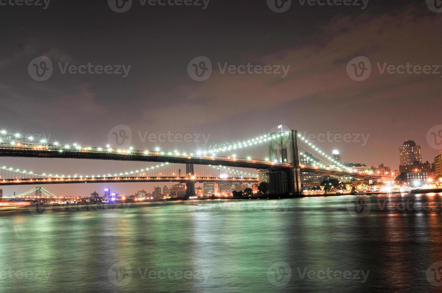 Brooklyn Bridge closeup over East River at night in New York City Manhattan with lights and reflections. photo