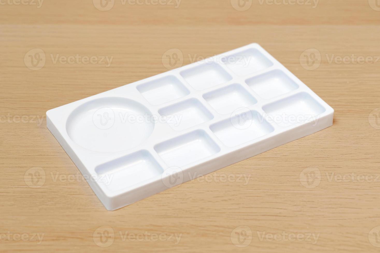 paleta de acuarela blanca. bandeja de acuarela vacía aislada sobre fondo de madera. paleta de pintura blanca. foto
