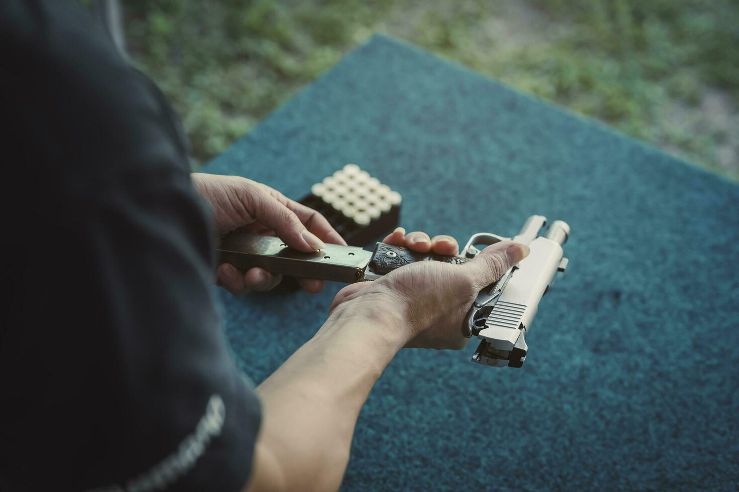 Shooter man loading In a gun magazine and black clothes prepare to shooting short gun at the shooting range. Shooting sports for meditation and self-defense, recreational activities. photo