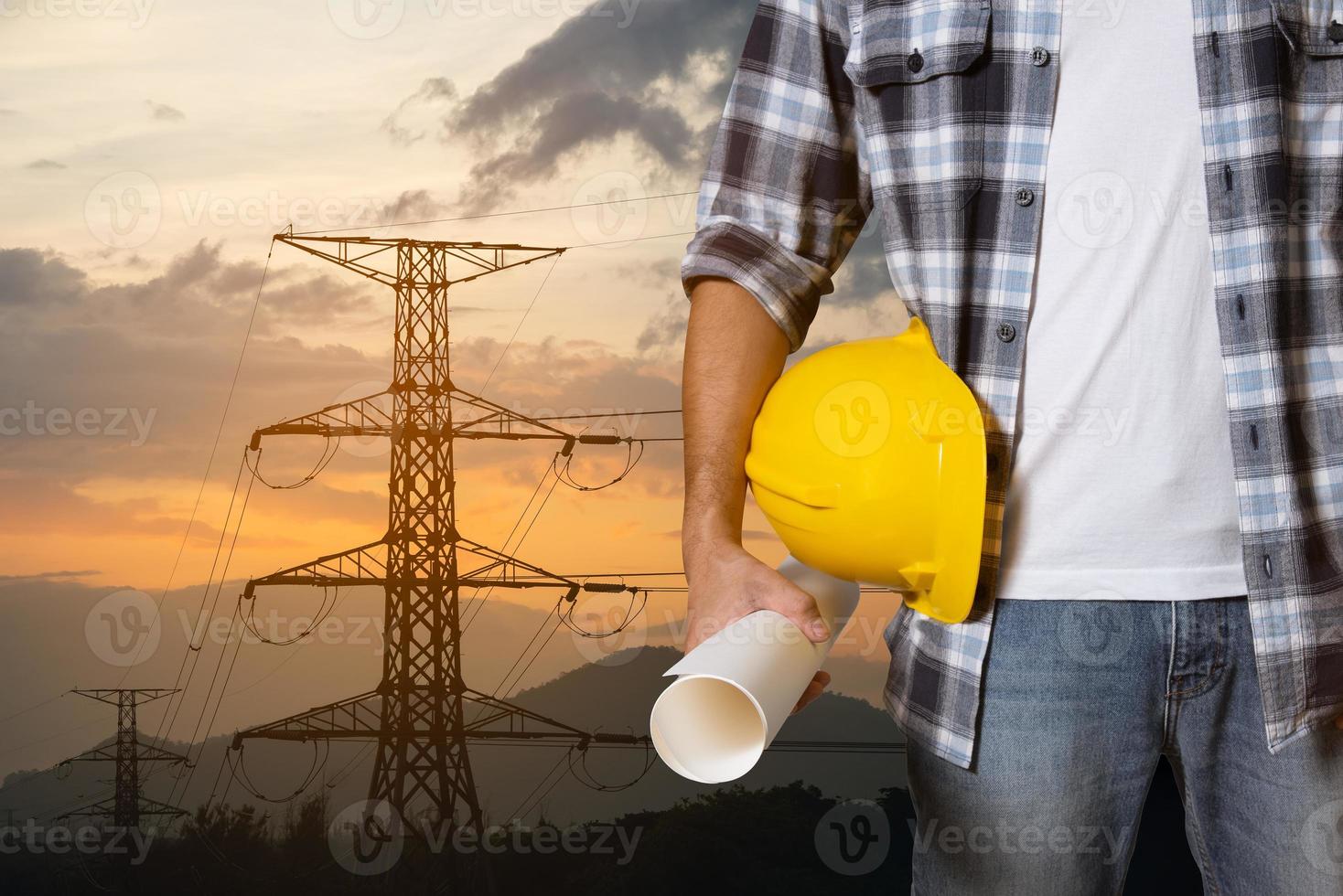 Engineer man construction hand holding yellow helmet hardhat on electric pole at power plant sunset background. Worker helmet Civil Construction Engineering. Close up engineer hand hold safety helmet. photo