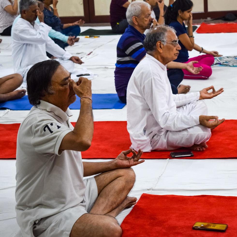 New Delhi, India, June 19 2022 -Group Yoga exercise session for people of different age groups in Balaji Temple, Vivek Vihar, International Yoga Day, Big group of adults attending yoga class in temple photo