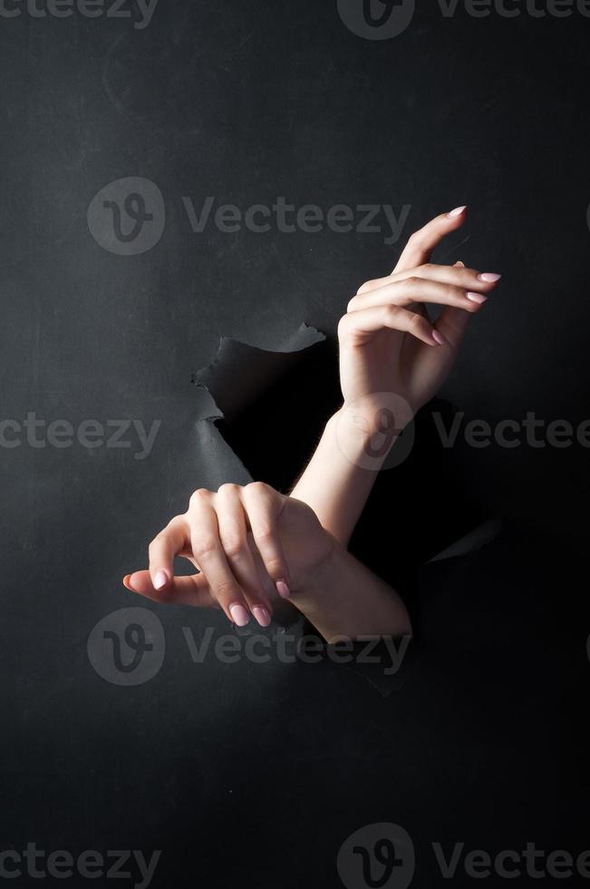 Female hands, on a black, torn background. photo