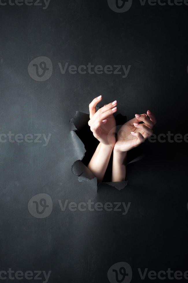 Female hands, on a black, torn background. photo