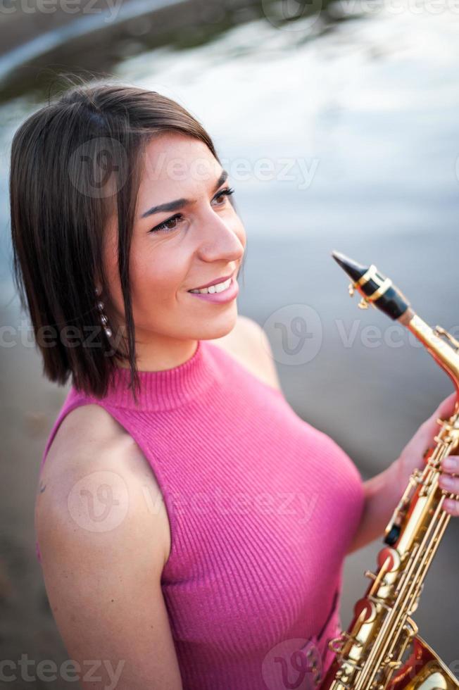 Woman playing the saxophone at sunset. photo