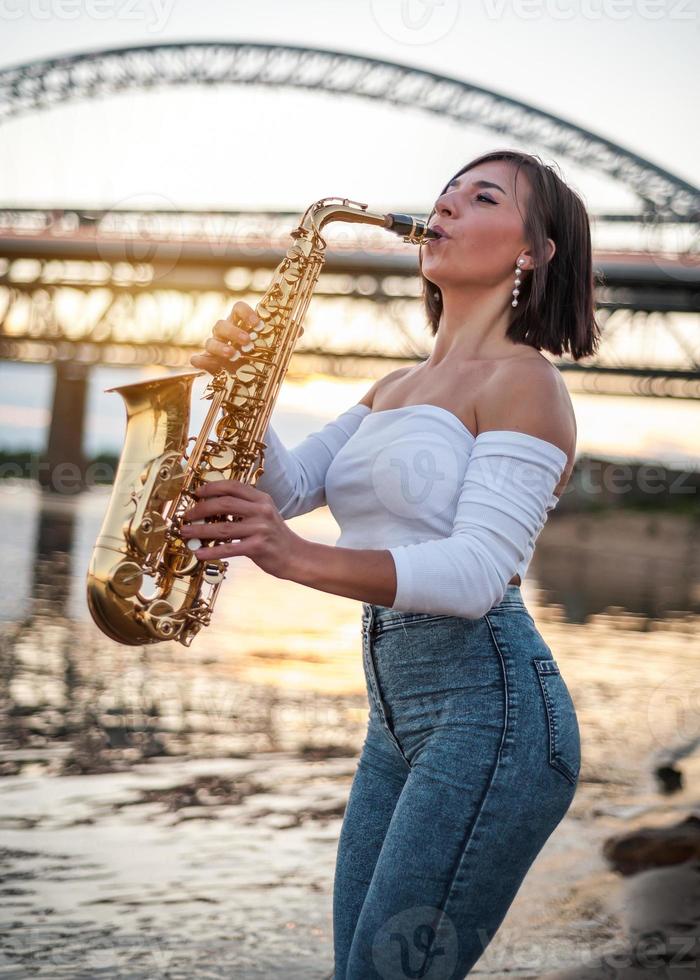 Woman playing the saxophone at sunset photo