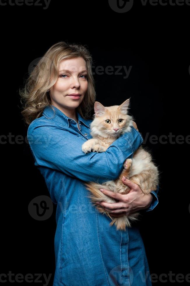Beautiful proprietress posing with her cat on a black background photo