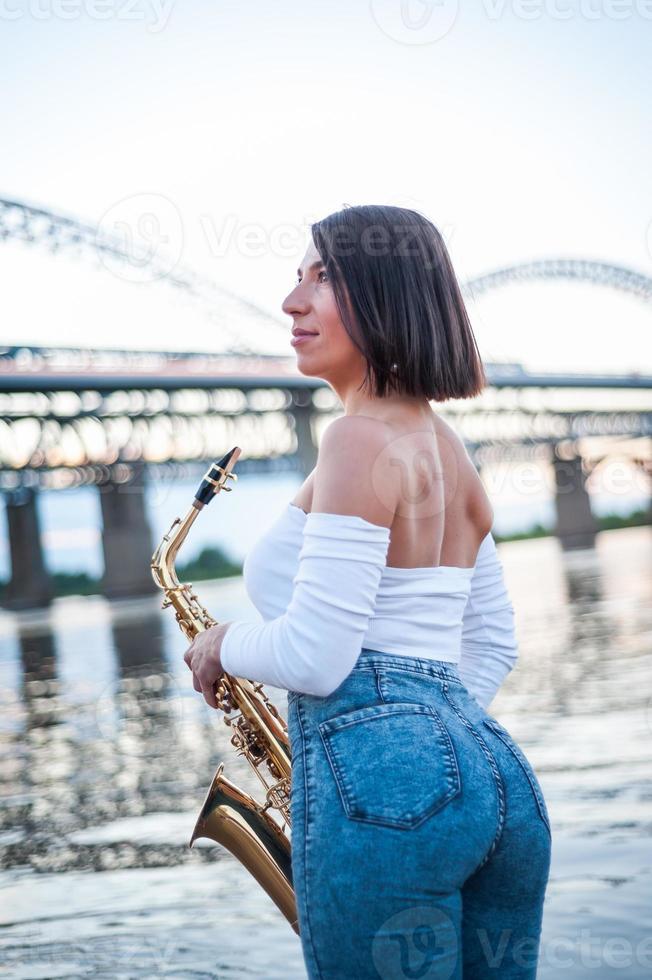 Woman playing the saxophone at sunset. photo