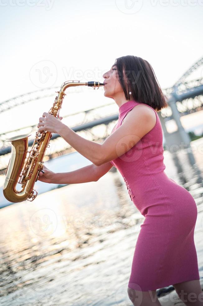 Woman playing the saxophone at sunset. photo