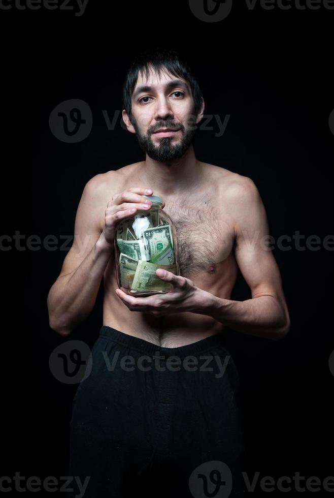 joven con botella de dinero sobre fondo negro foto