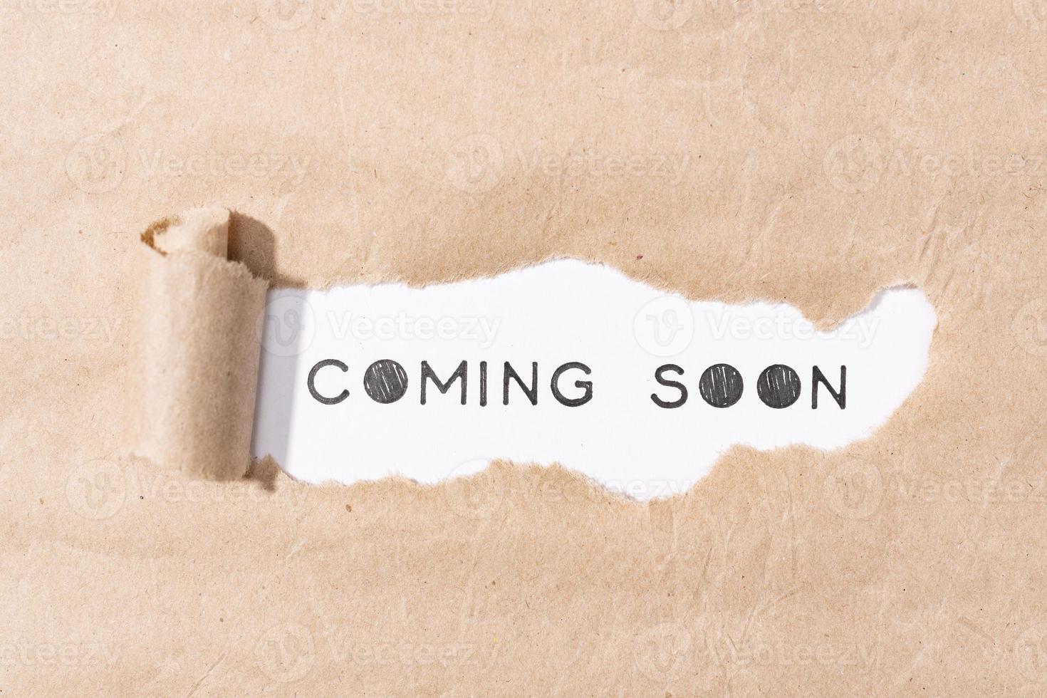 Coming soon message on torn paper photo