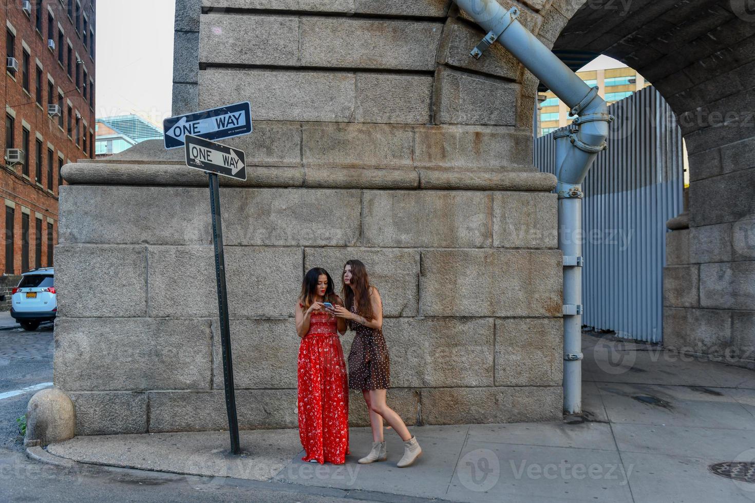 dos chicas perdidas interactuando con un teléfono móvil para obtener direcciones en la ciudad de nueva york foto