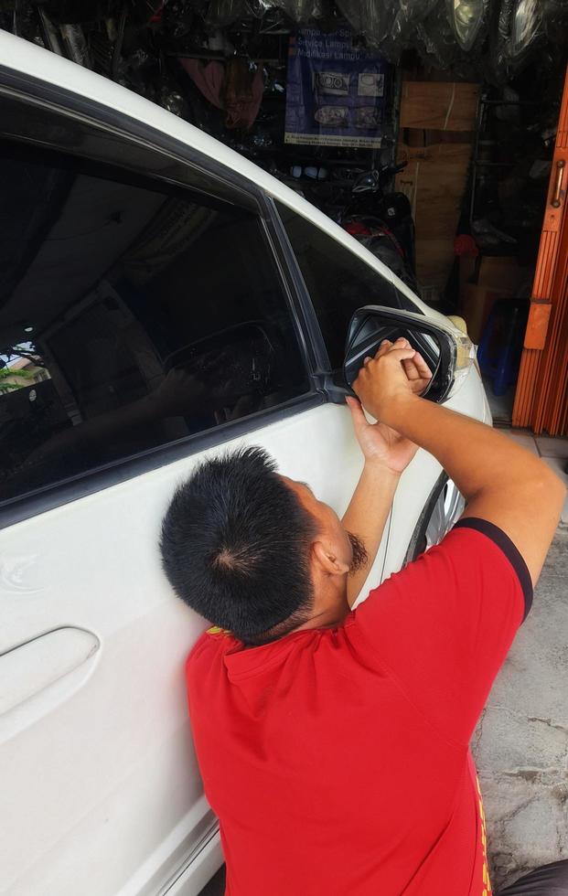 Yogyakarta, Indonesia on July 2022.  A repairman is installing a new rearview mirror photo