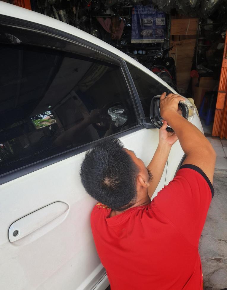 Jakarta, Indonesia on July 2022. A repairman is installing a new rearview mirror photo