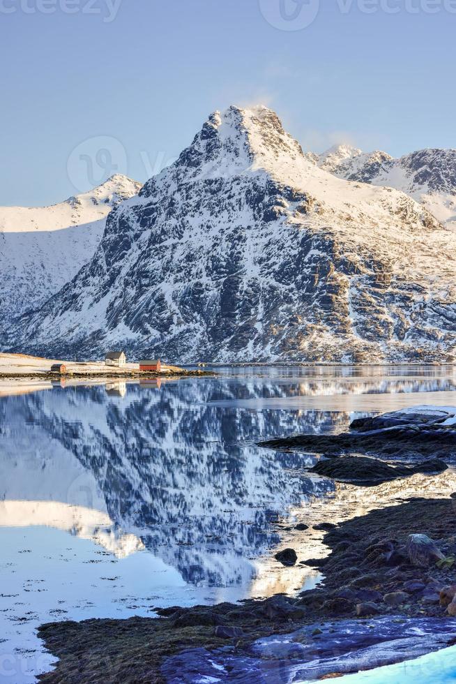 impulsado por bo con montañas reflejadas en el agua. en las islas lofoten, noruega en el invierno. foto