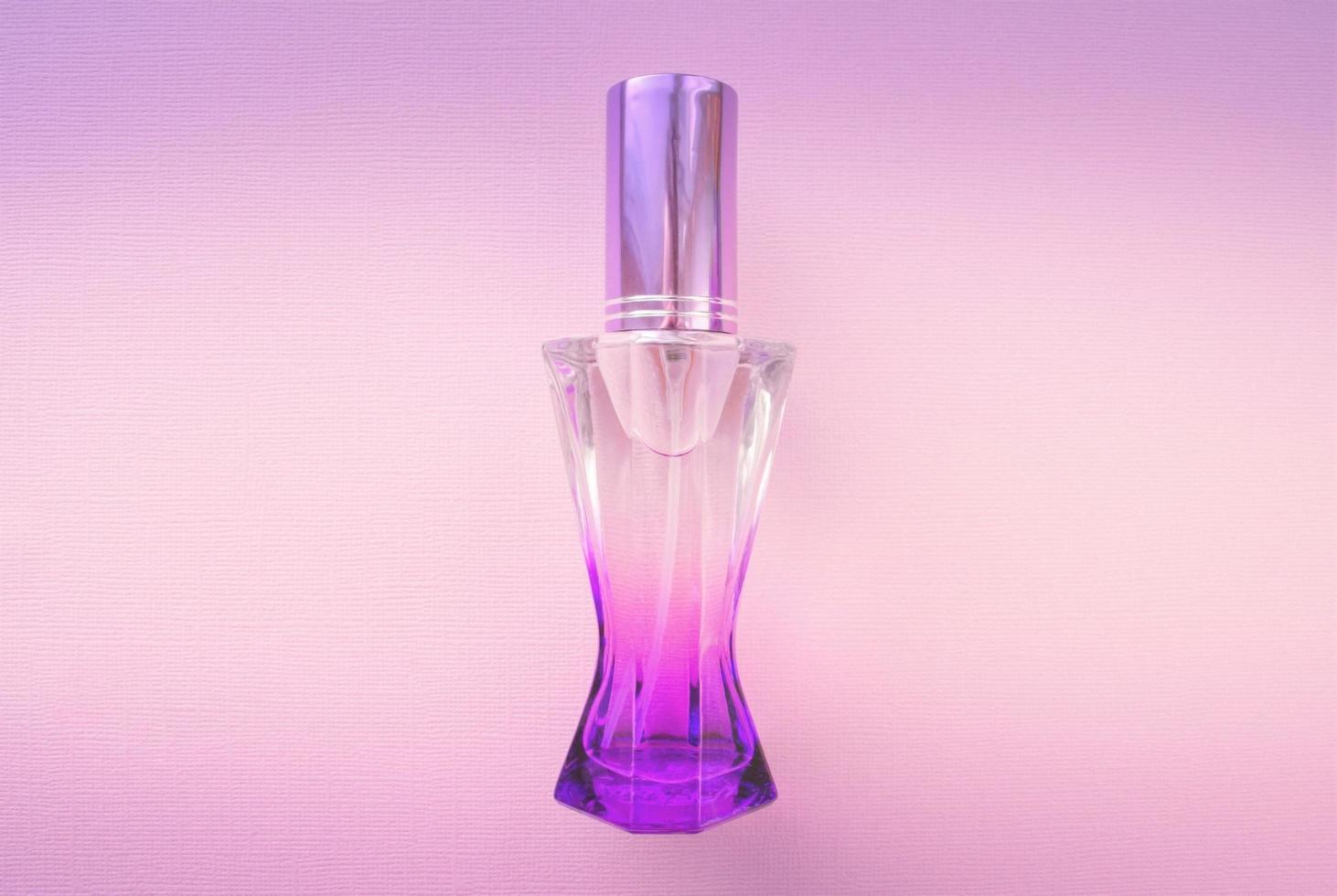botella de perfume sobre un fondo rosa. perfume femenino. Frasco de perfume violeta. foto