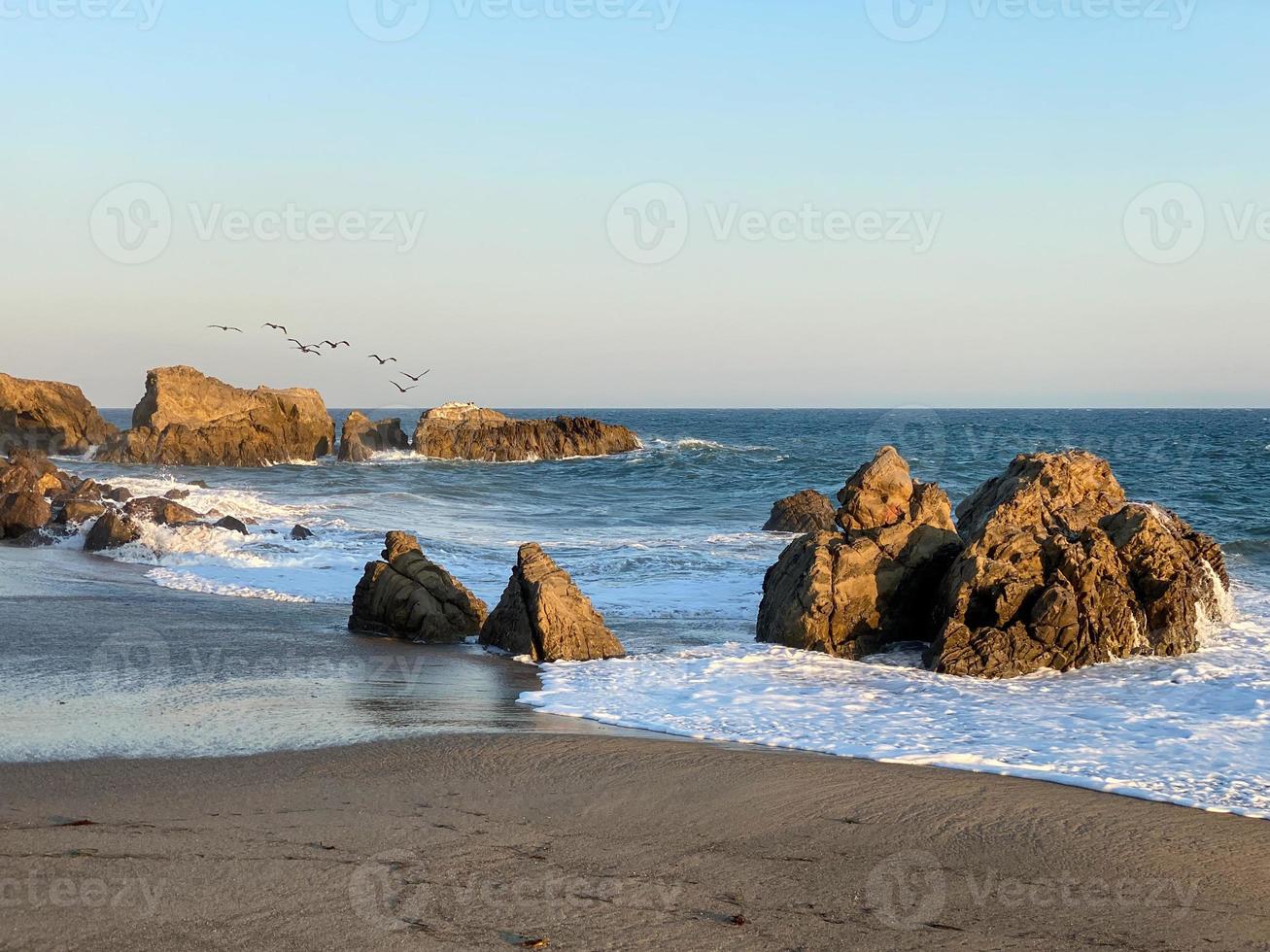 Impresionante vista de larga exposición de olas suaves que chocan contra formaciones rocosas al atardecer, punto sequit, playa estatal leo carrillo, malibu, california foto