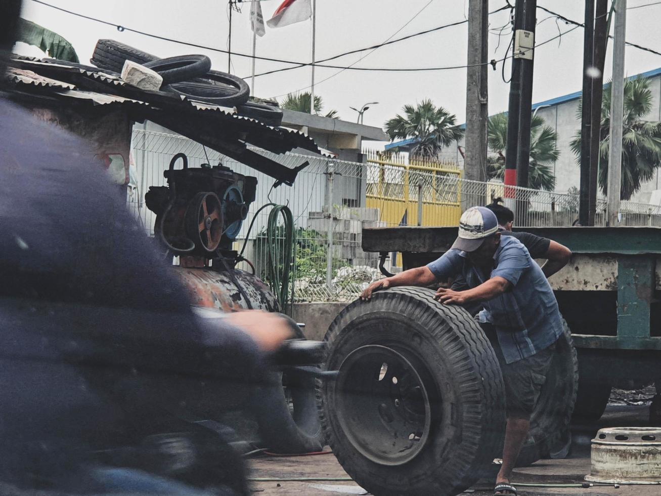 yakarta, indonesia en julio de 2022. dos hombres estaban reemplazando un neumático de camión reventado. foto