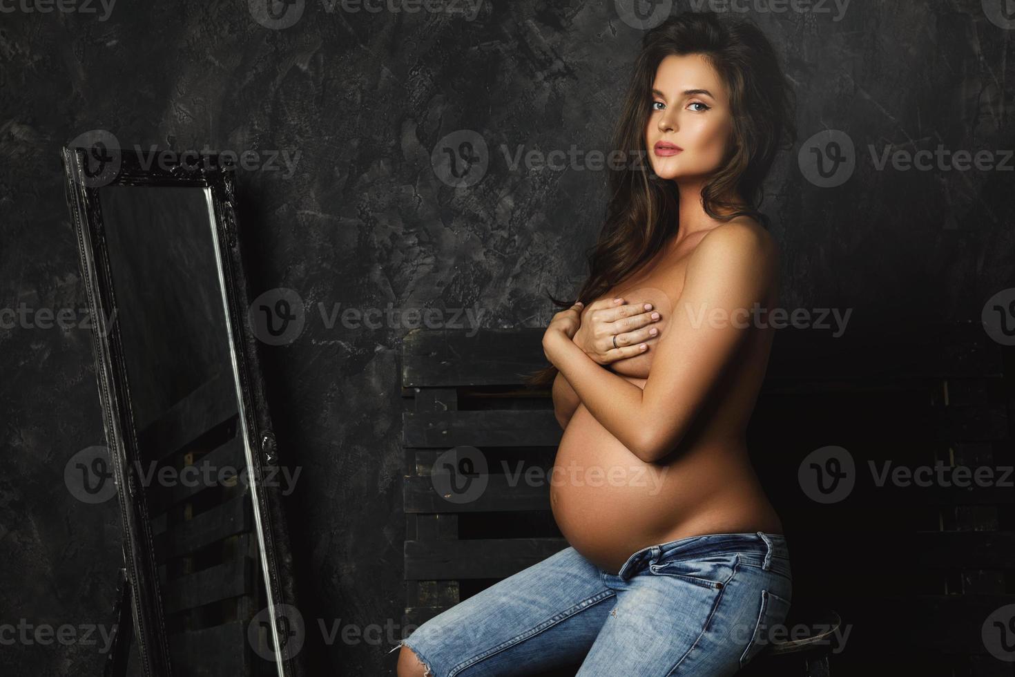 Portrait of young pregnant woman wearing jeans with beautiful long hair photo