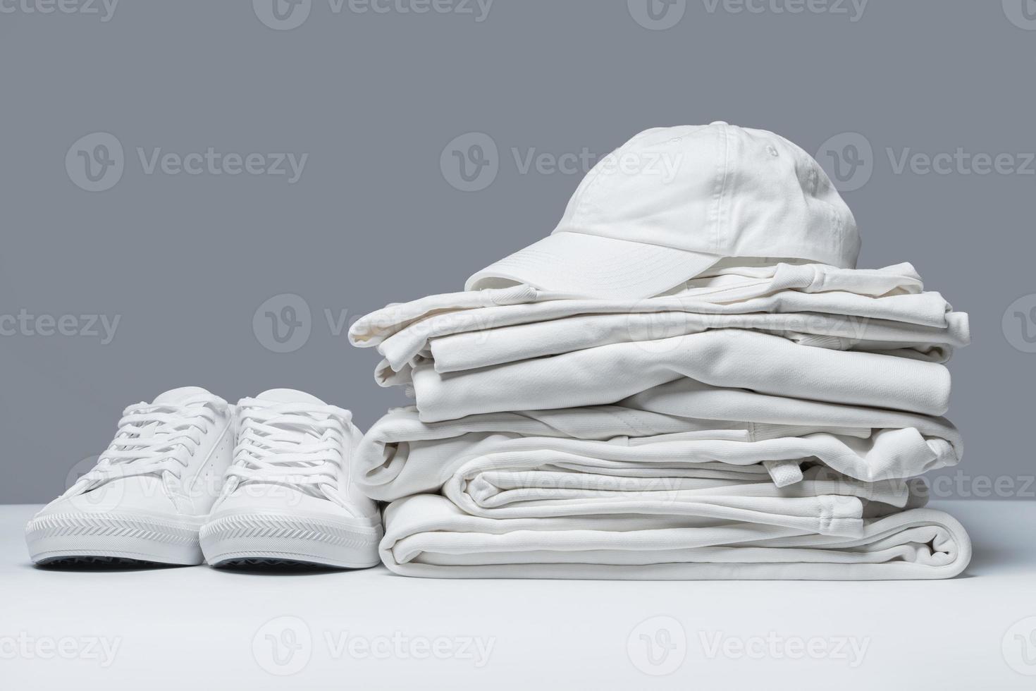 pila de ropa blanca, entrenadores y gorra de béisbol foto