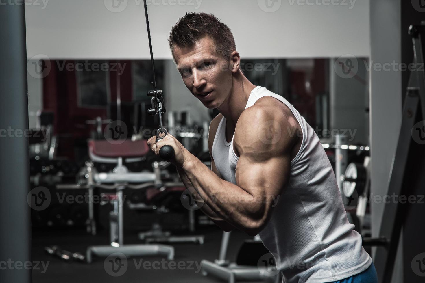 Muscular man during workout in the gym photo