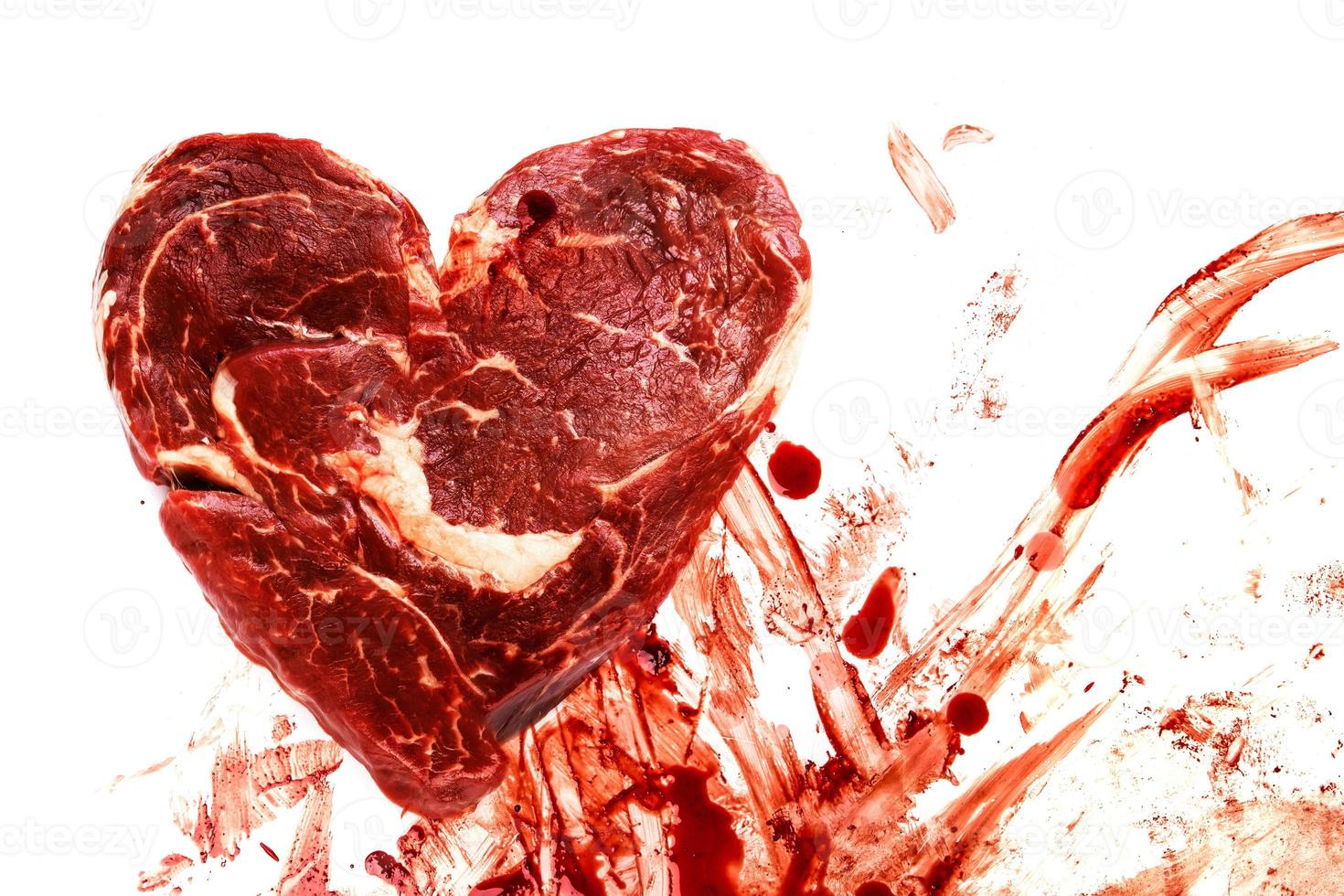 Fresh raw meat in shape of heart and blood splatters photo