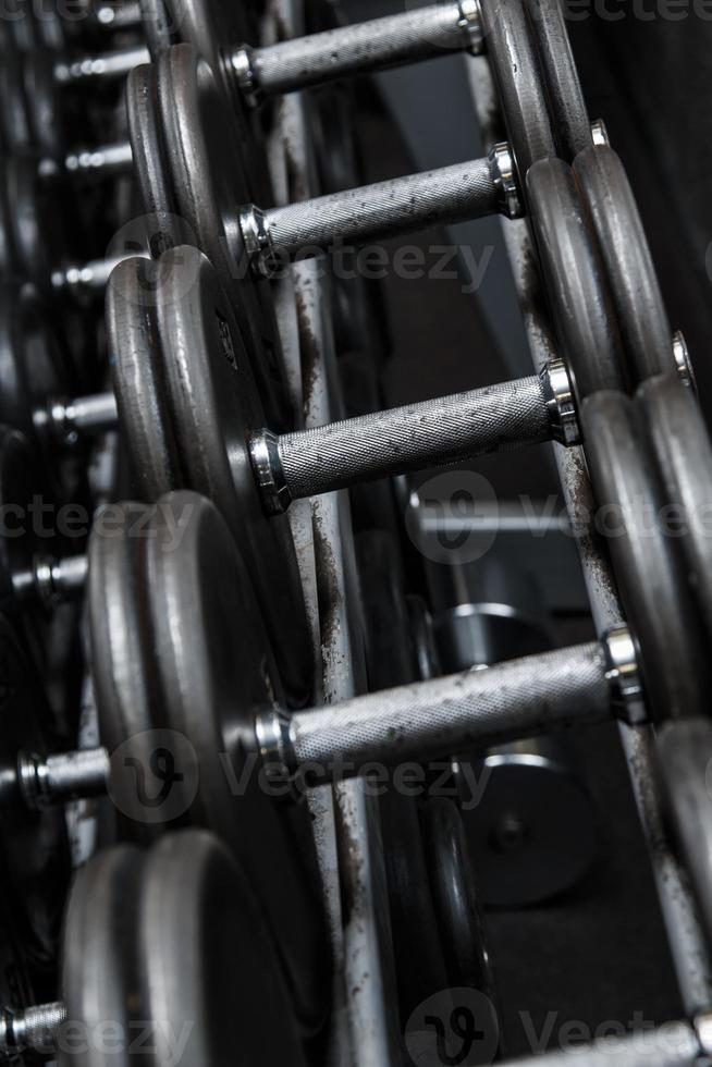 Different black dumbbells in the modern gym photo