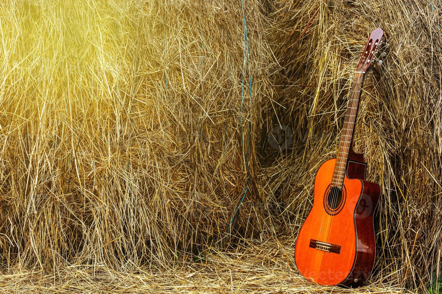 Acoustic guitar and haystacks in the village photo