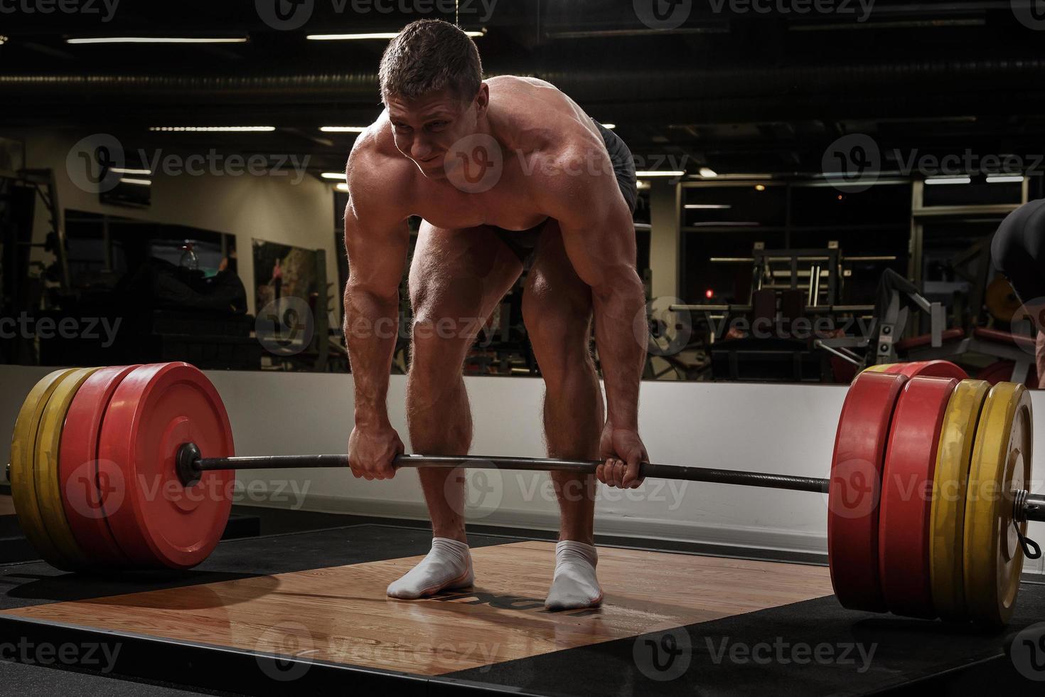 Strong man doing deadlift exercise in the gym photo