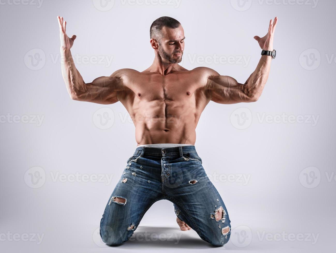 Handsome muscular man wearing jeans posing in studio photo