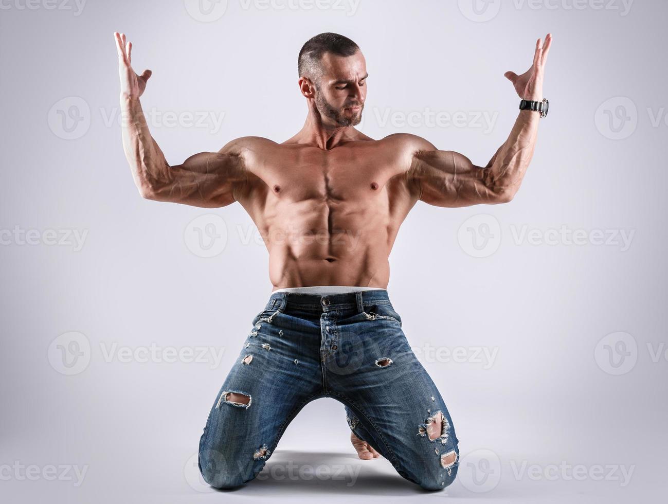 Handsome muscular man wearing jeans posing in studio photo