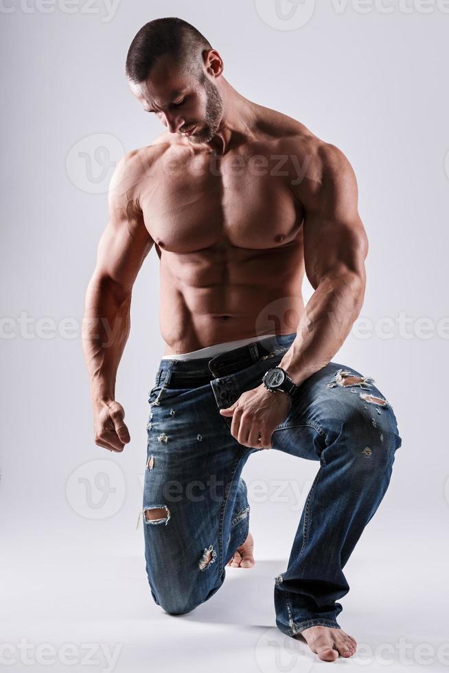 hombre musculoso guapo con jeans posando en el estudio foto