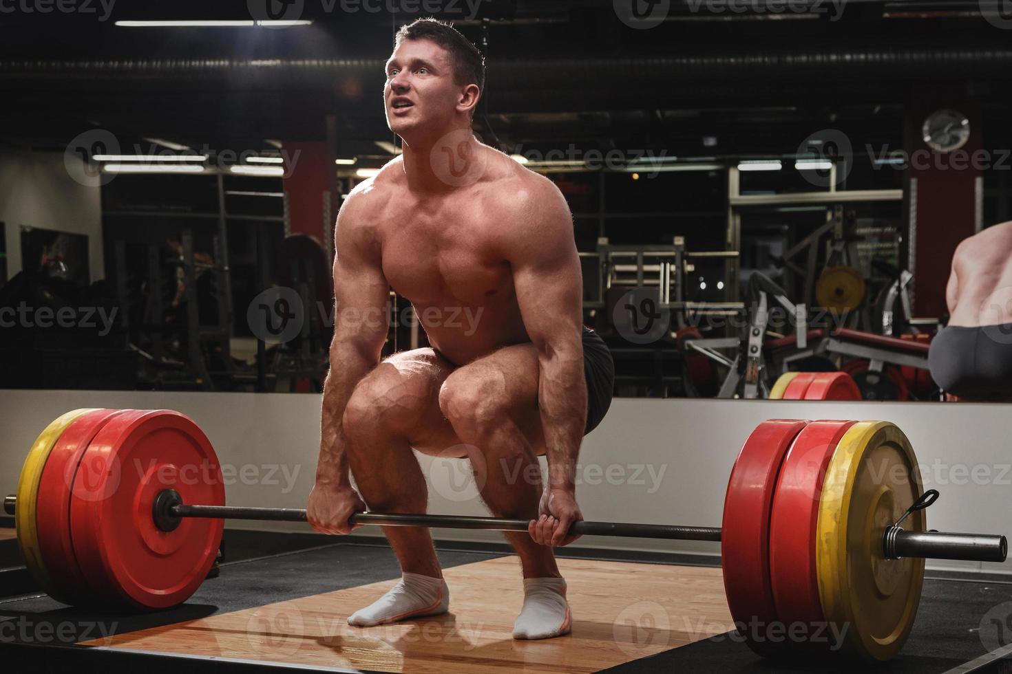 Strong man doing deadlift exercise in the gym photo