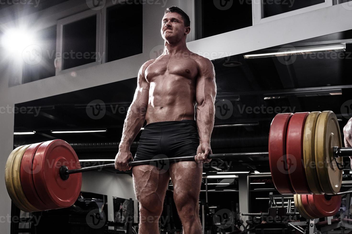 Strong man doing deadlift exercise in the gym photo