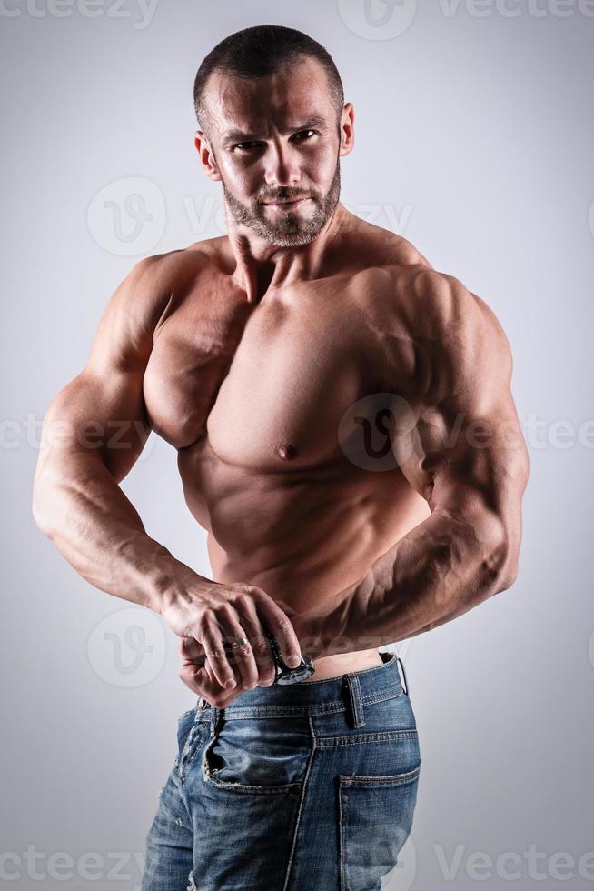 Handsome muscular man wearing jeans posing in studio photo