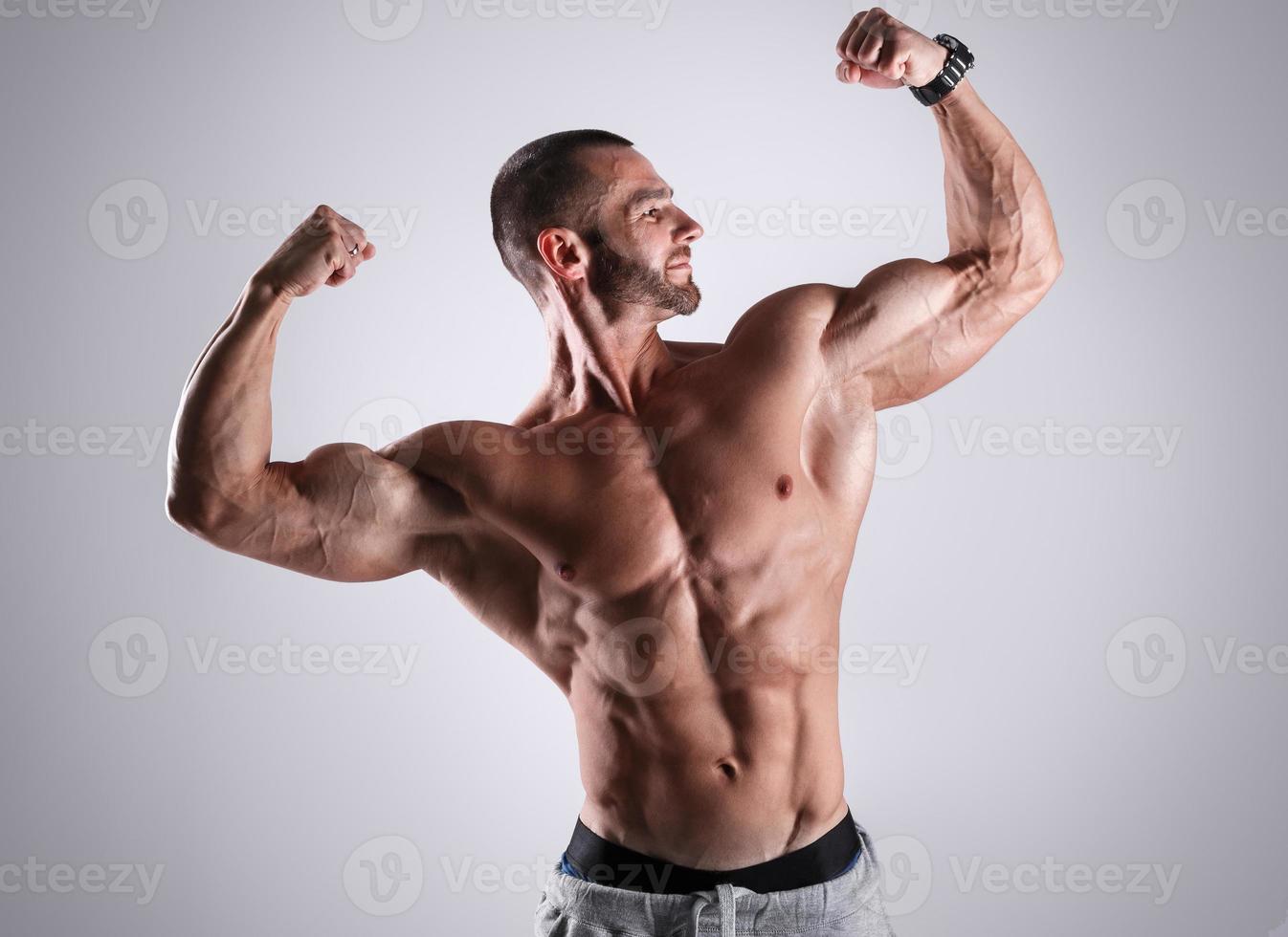 Handsome muscular man posing in studio against gray background photo