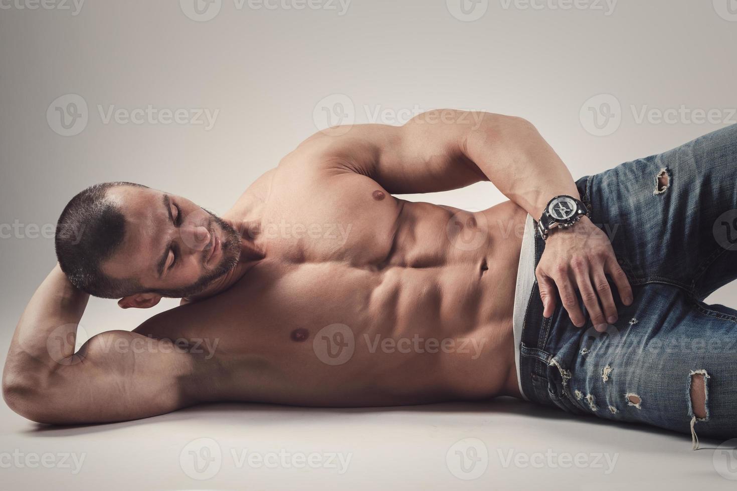 Handsome muscular man posing in studio on gray background photo