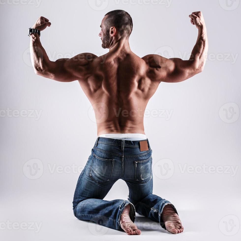 hombre musculoso guapo posando en estudio sobre fondo gris foto