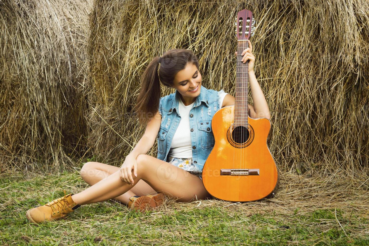 mujer joven y feliz tocando la guitarra en el pueblo foto