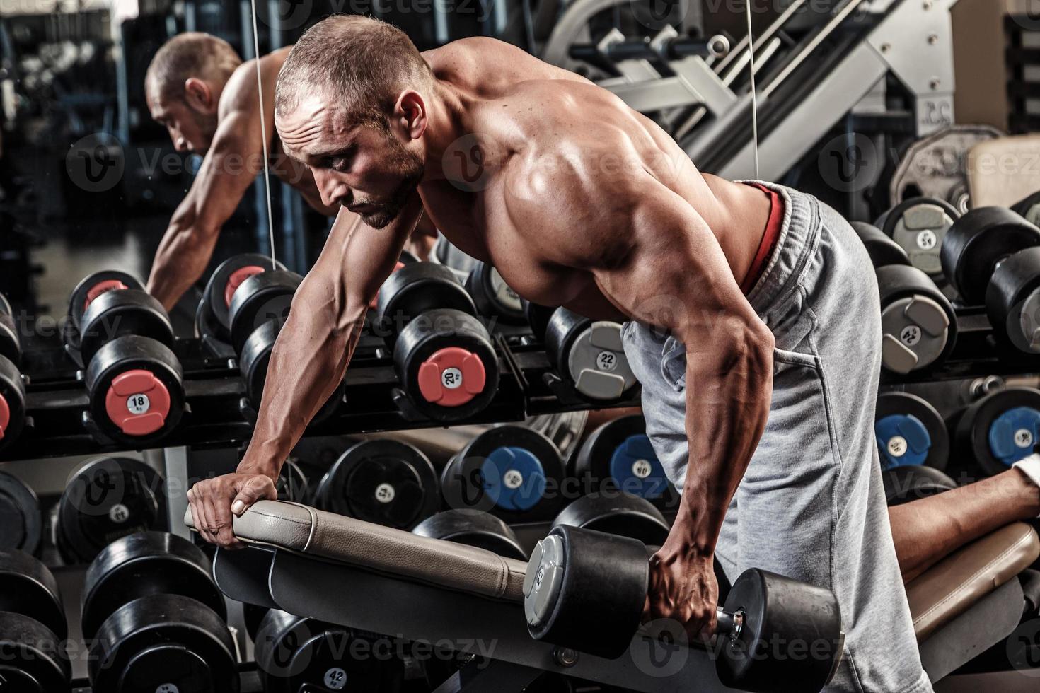Young and muscular man working out with dumbbell photo