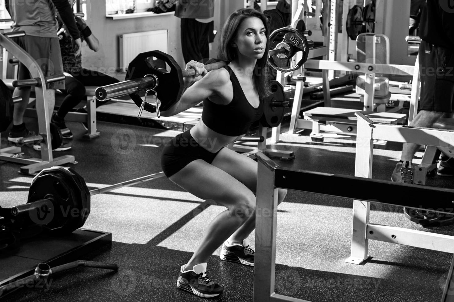 Beautiful woman with barbell on her shoulders photo