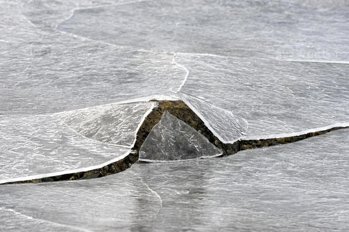 Rock cracking through the ice in Vagspollen in the Lofoten Islands, Norway in the winter. photo