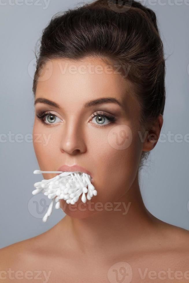 mujer joven con la boca llena de hisopos de algodón foto