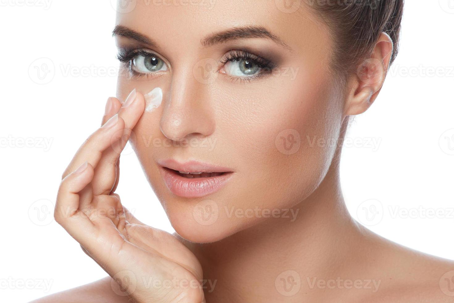 mujer joven y hermosa aplicando crema hidratante en la cara foto