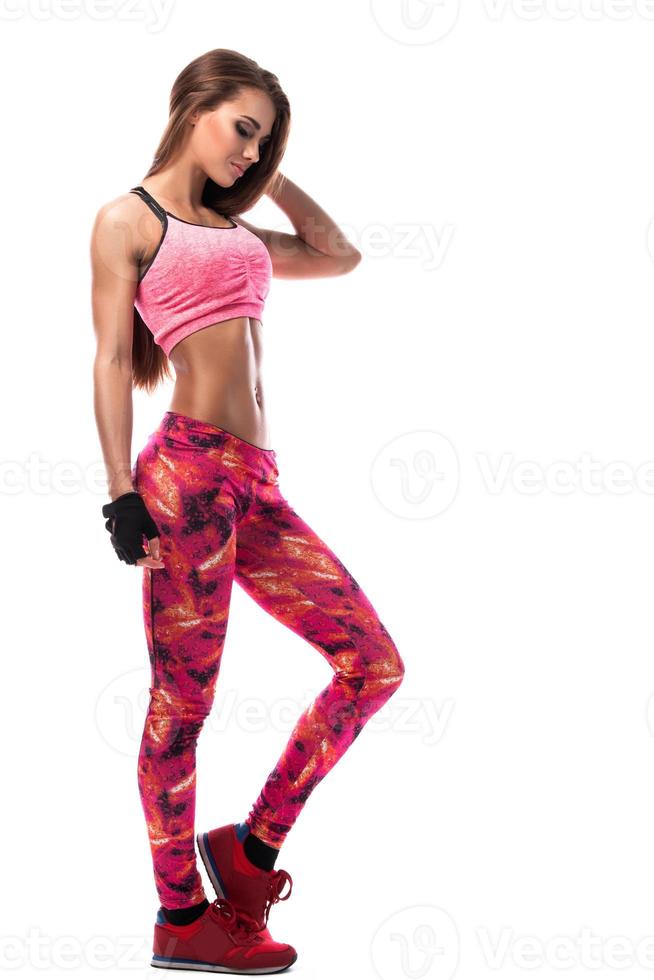 Beautiful fitness girl wearing pink outfit in studio photo