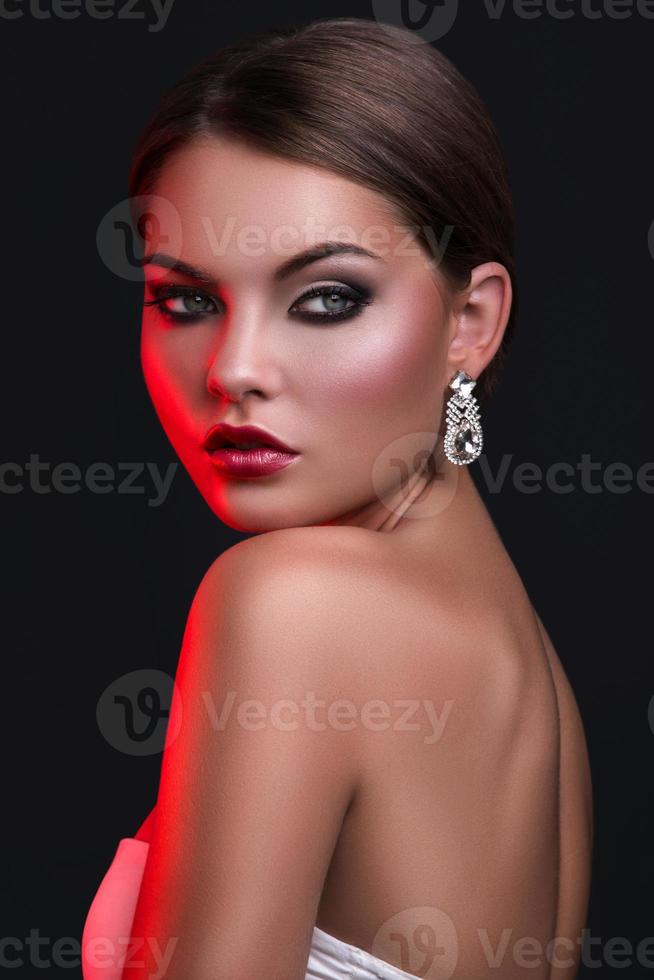 Woman with beautiful earrings in red light photo