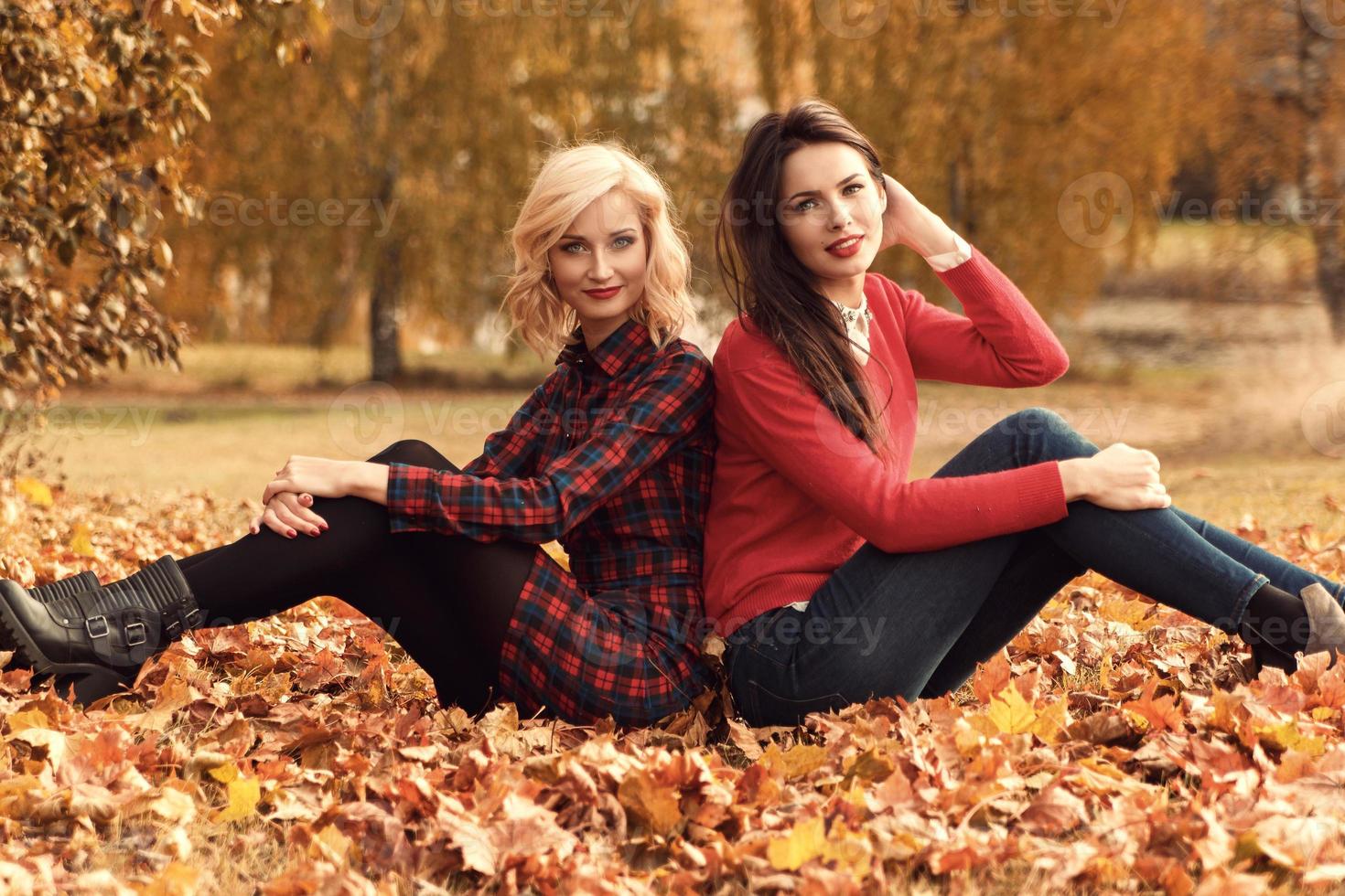 Two beautiful girls friends having fun in autumn park photo