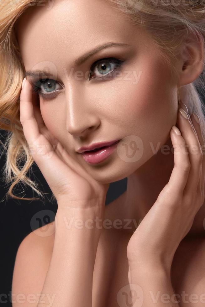 Blonde girl with pretty face on dark background photo