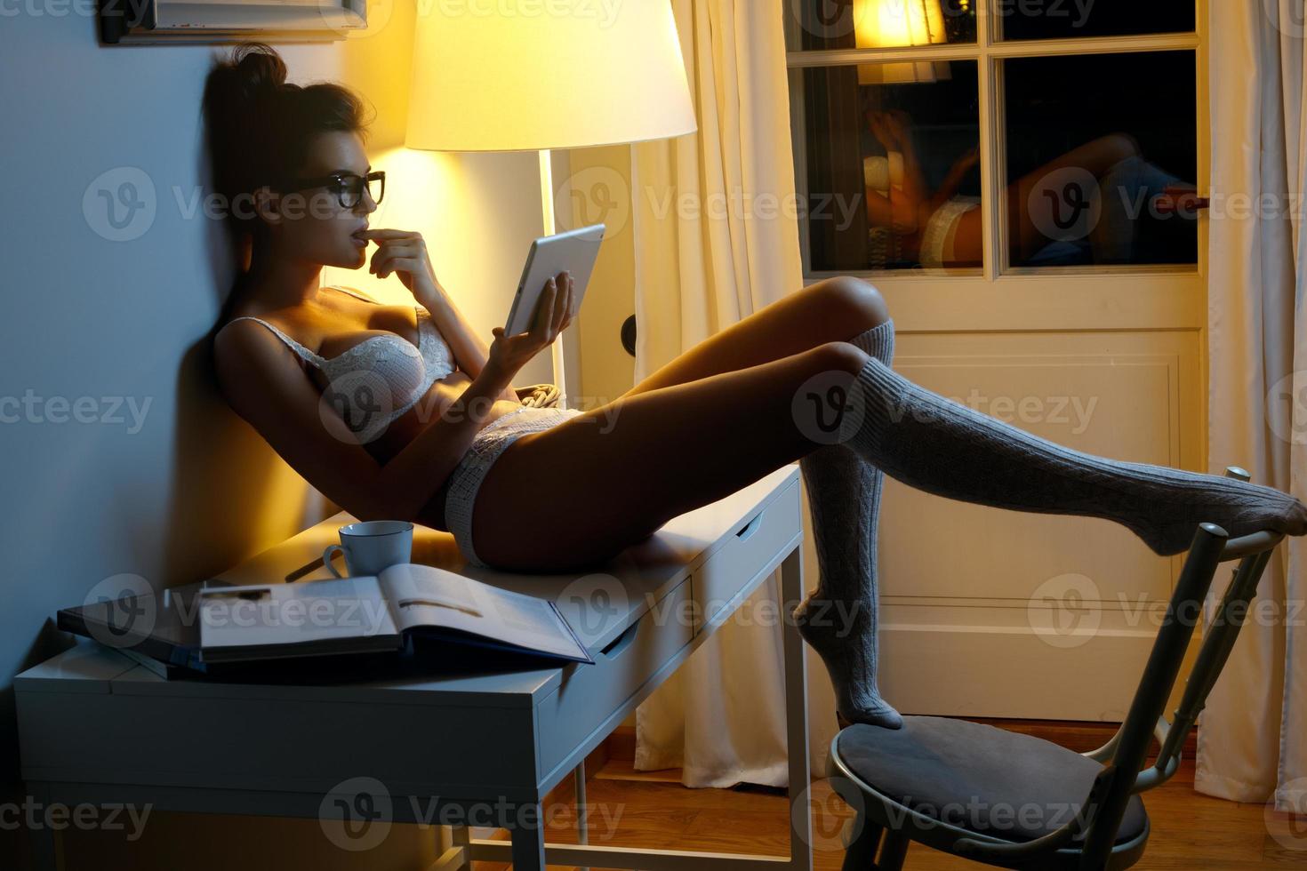 Sexy woman in lingerie is using tablet at late night photo