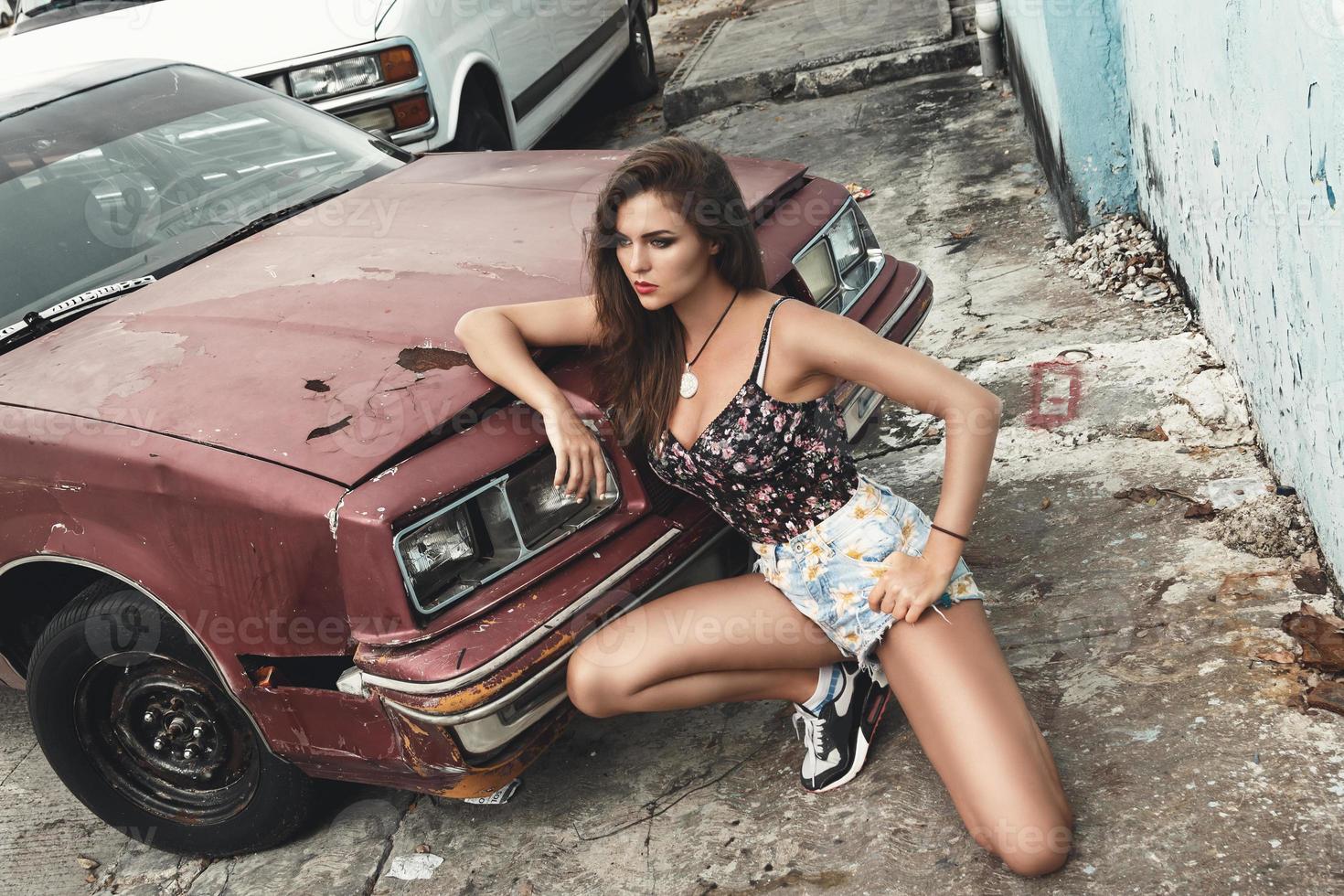 mujer y viejo coche oxidado en la calle foto