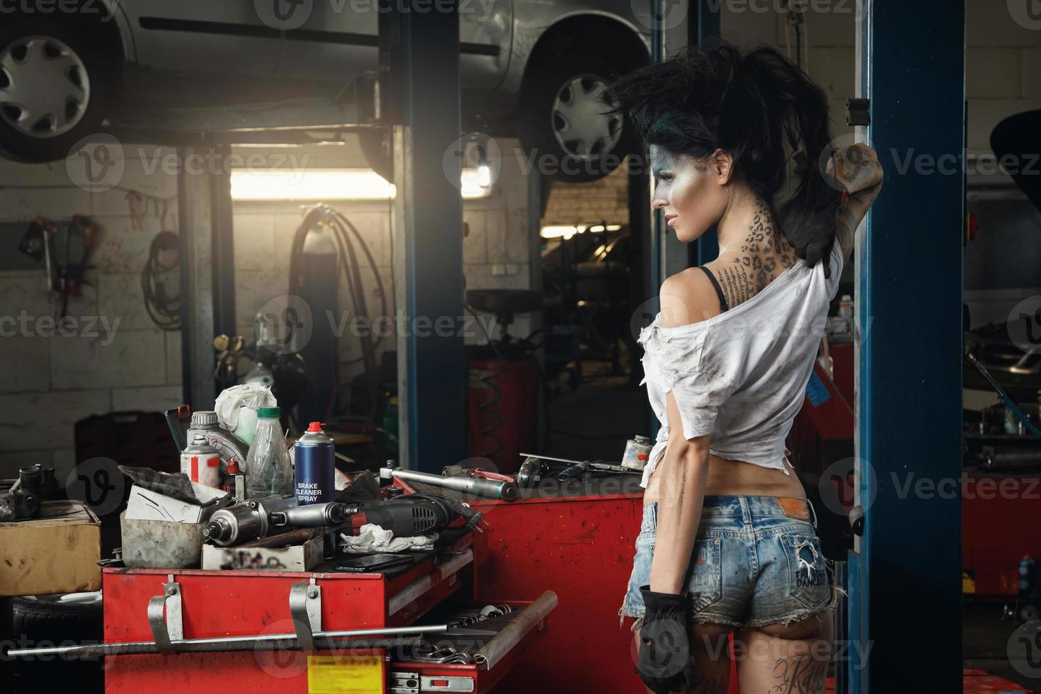 Woman mechanic in garage with artistic makeup on her face stylized like a dirty spot photo